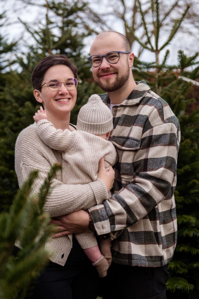 Familie beim Weihnachts-Fotoshooting zwischen Tannenbäumen